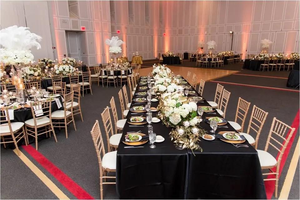 Long tables with black cloth and gold chairs. 