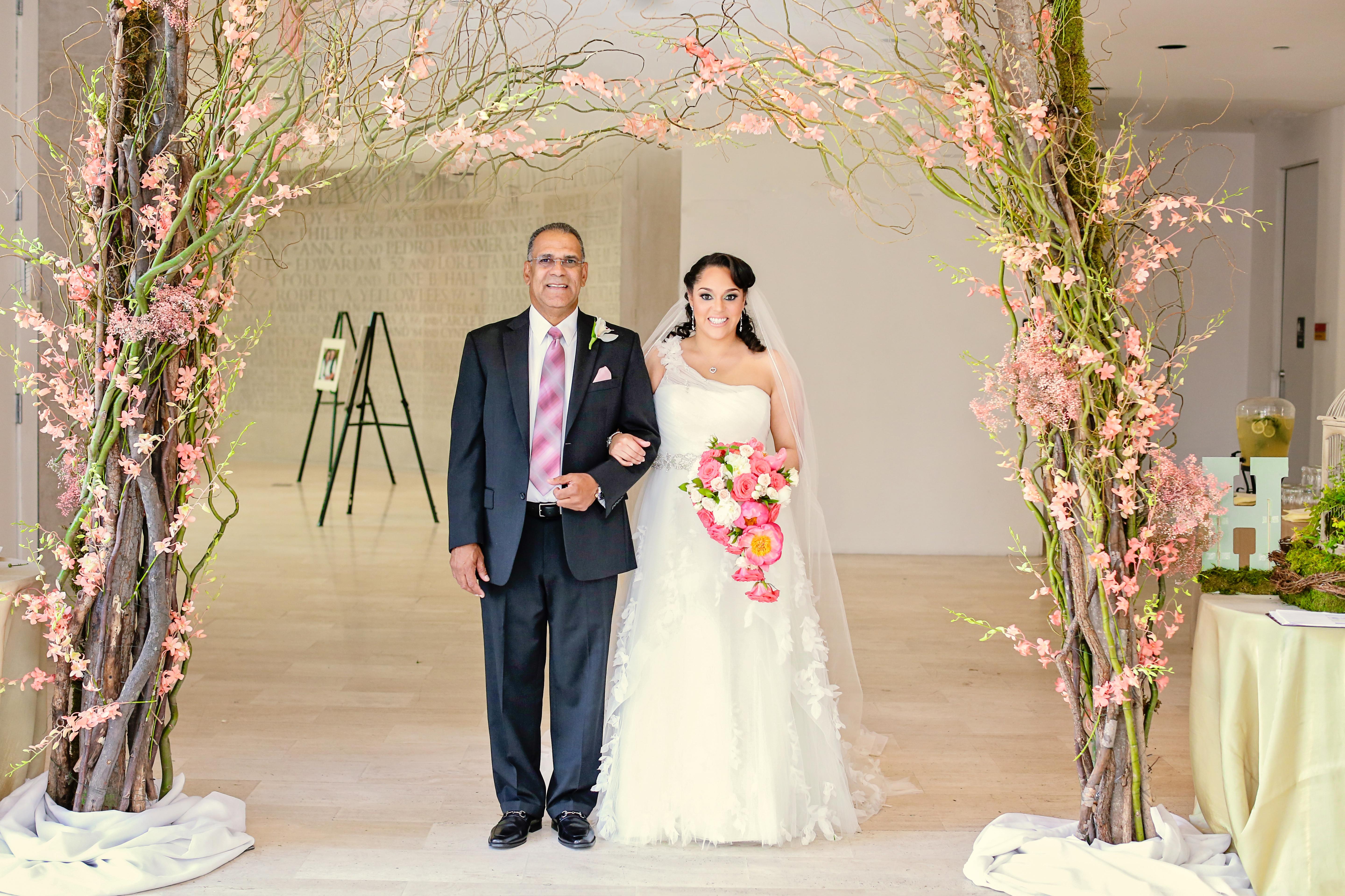 Bride with father walking under floral arch