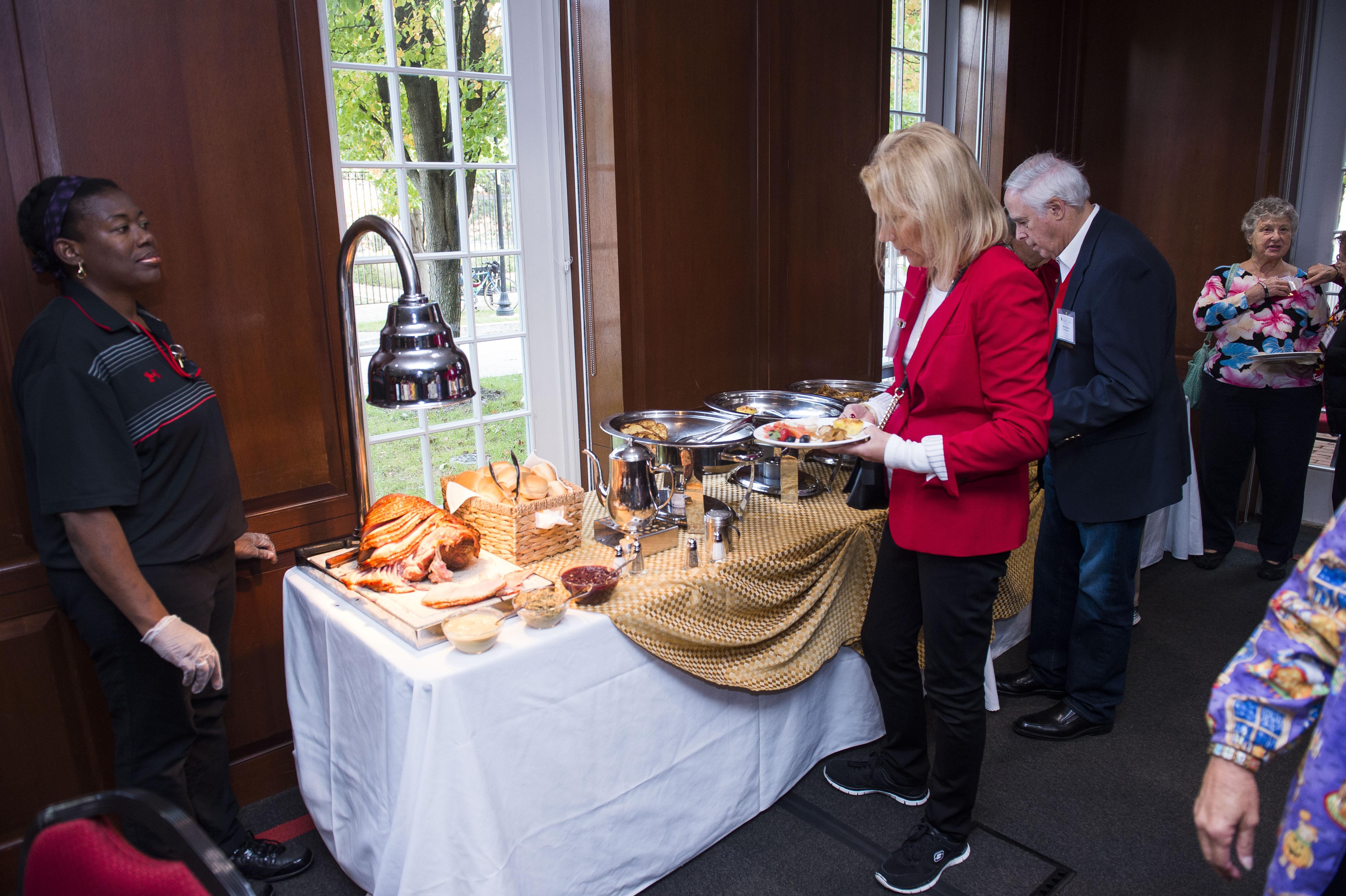 People being served at buffet with carved ham