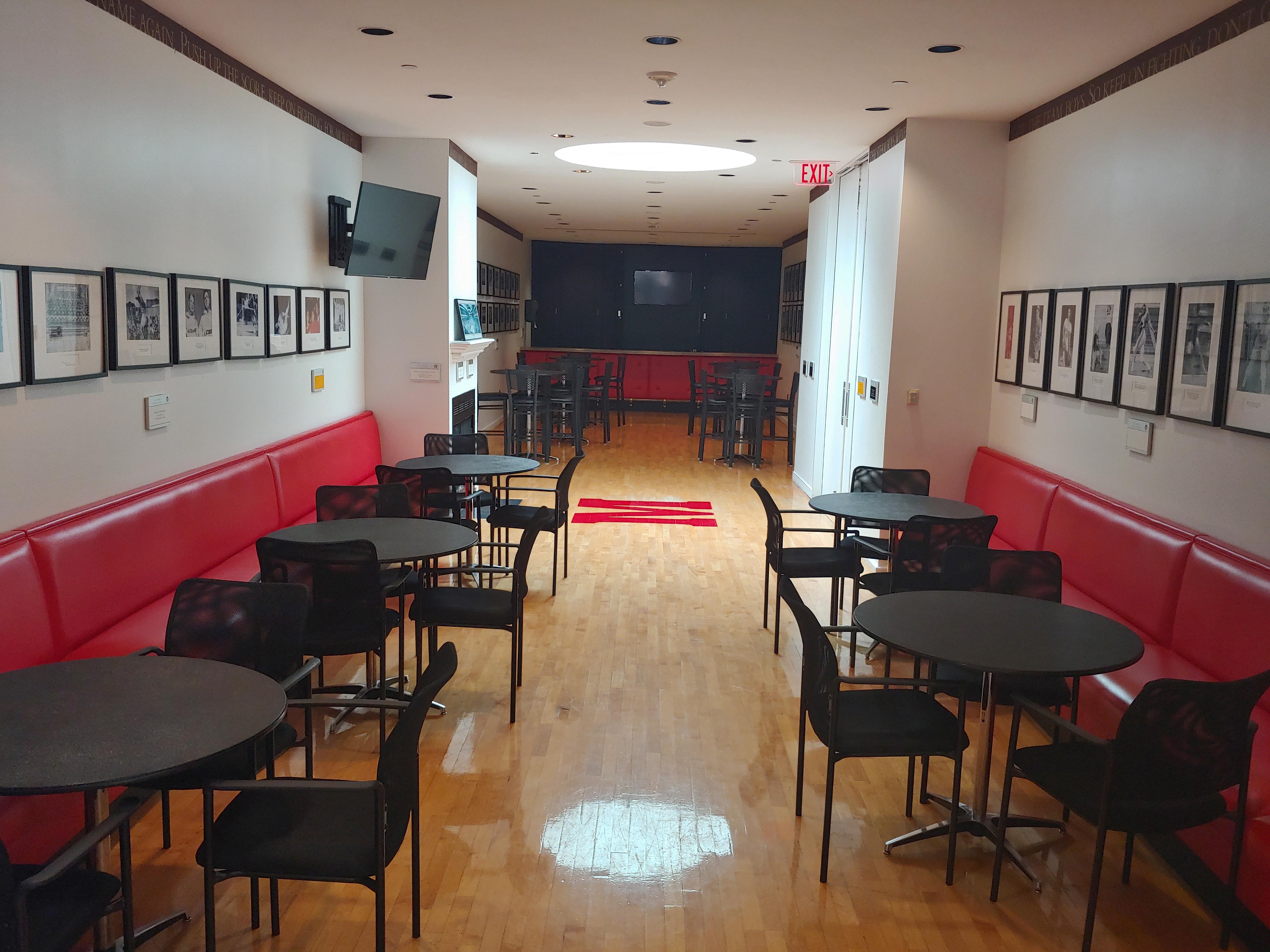 Sports bar with low black tables and chairs and red benches lining the wall
