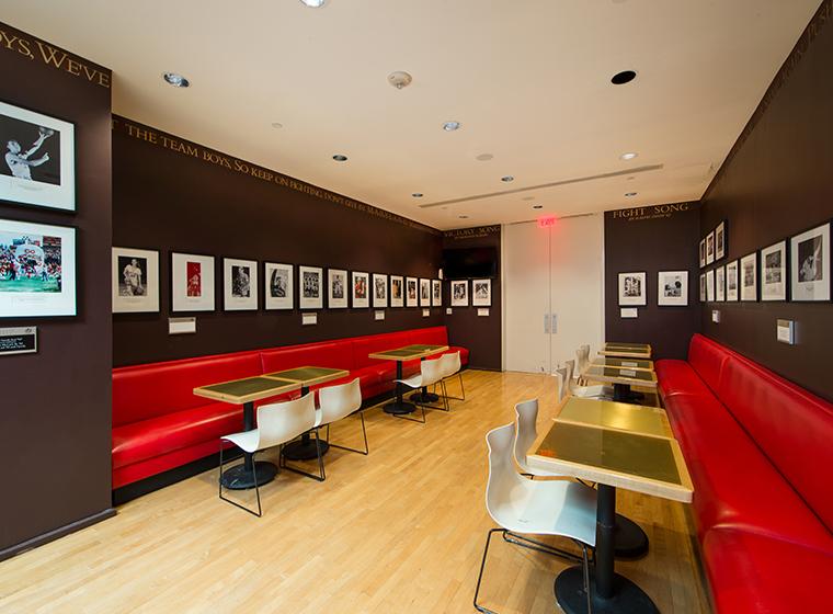 Sports club containing red benches, photographic memorabilia and hardwood floors
